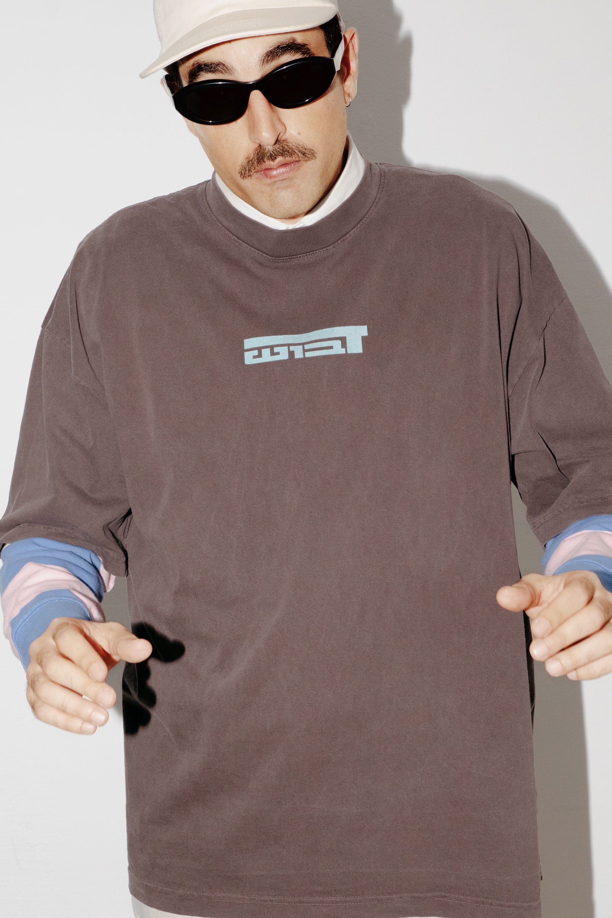 A model wearing an oversized DABUSH t-shirt in washed brown, made from 100% cotton.
דוגמן לובש טישרט אוברסייז של דבוש בצבע חום שטוף, עשויה 100% כותנה עם לוגו בצבע תכלת.